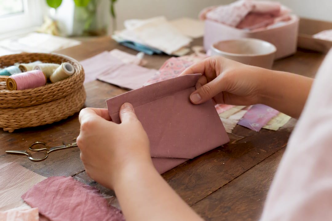 Close-up of hands sewing snap on oilcloth cash envelope