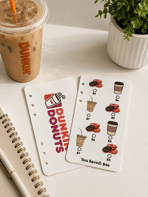 Coffee Run A6 savings challenge displayed with an iced coffee and plant on a white desk